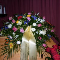Trauerkranz mit vielen farbigen Blüten auf einem Sarg