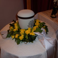 Blumenkranz mit gelben Blüten um eine Urne