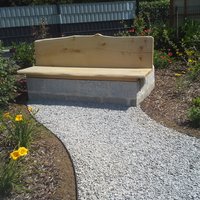 Gartenbank umringt von einem Beet und einem Kiesweg